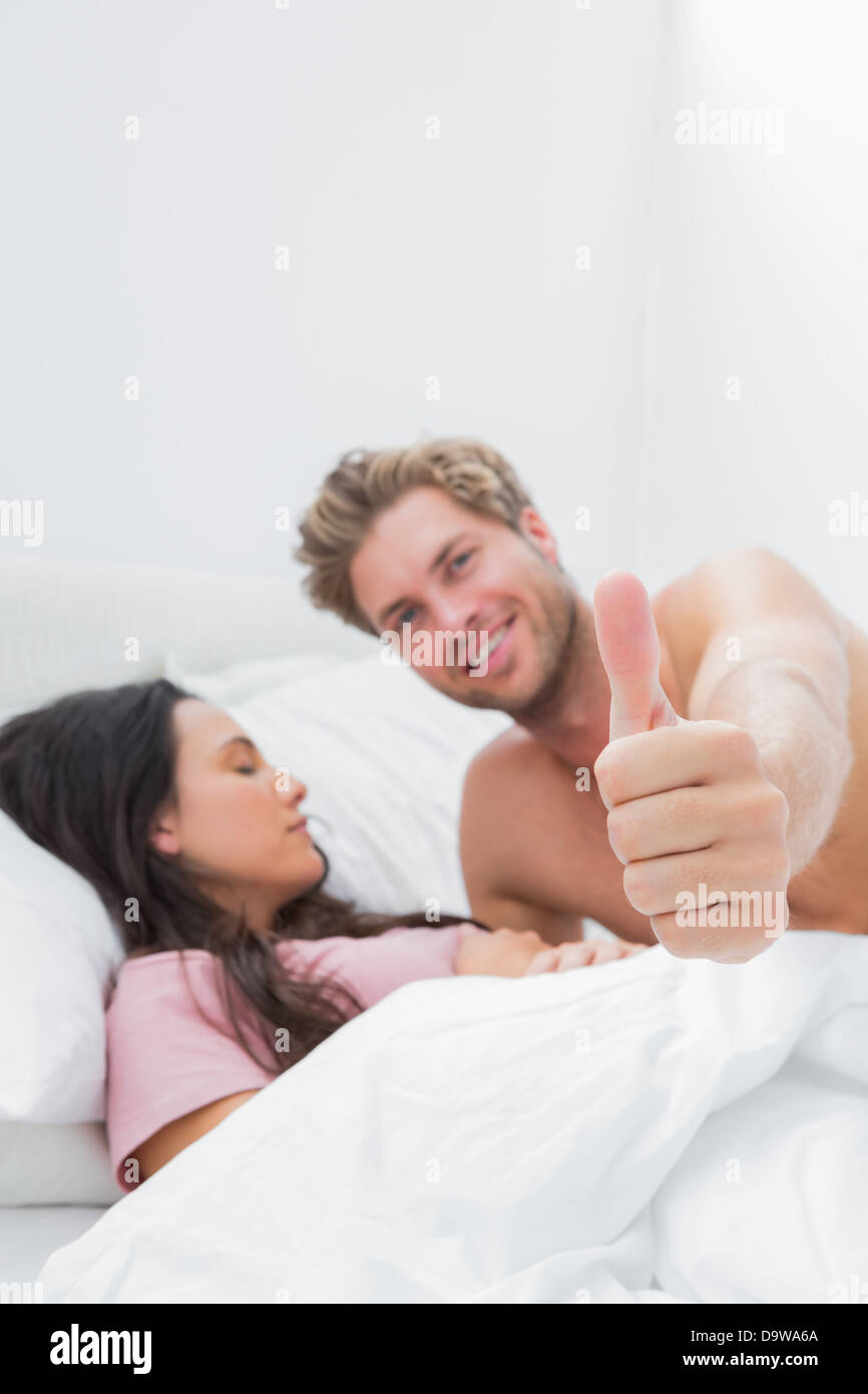 Man giving thumb up next to his sleeping partner Stock Photo