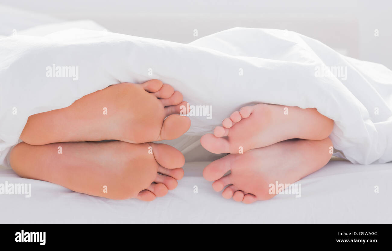 Feet of partners under the quilt Stock Photo