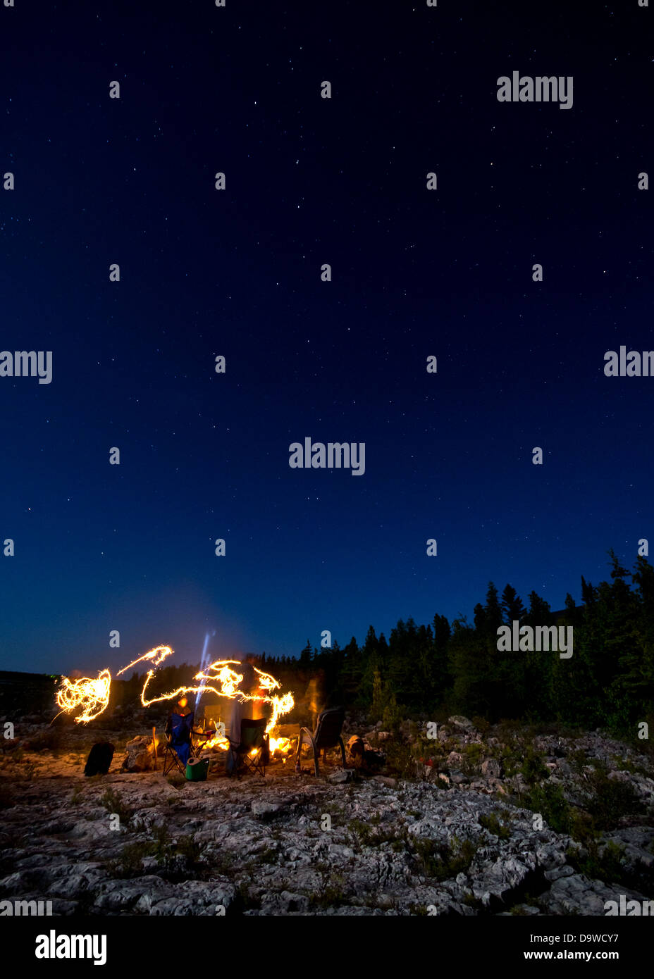 A group of people around a camp fire with sparklers. Stock Photo