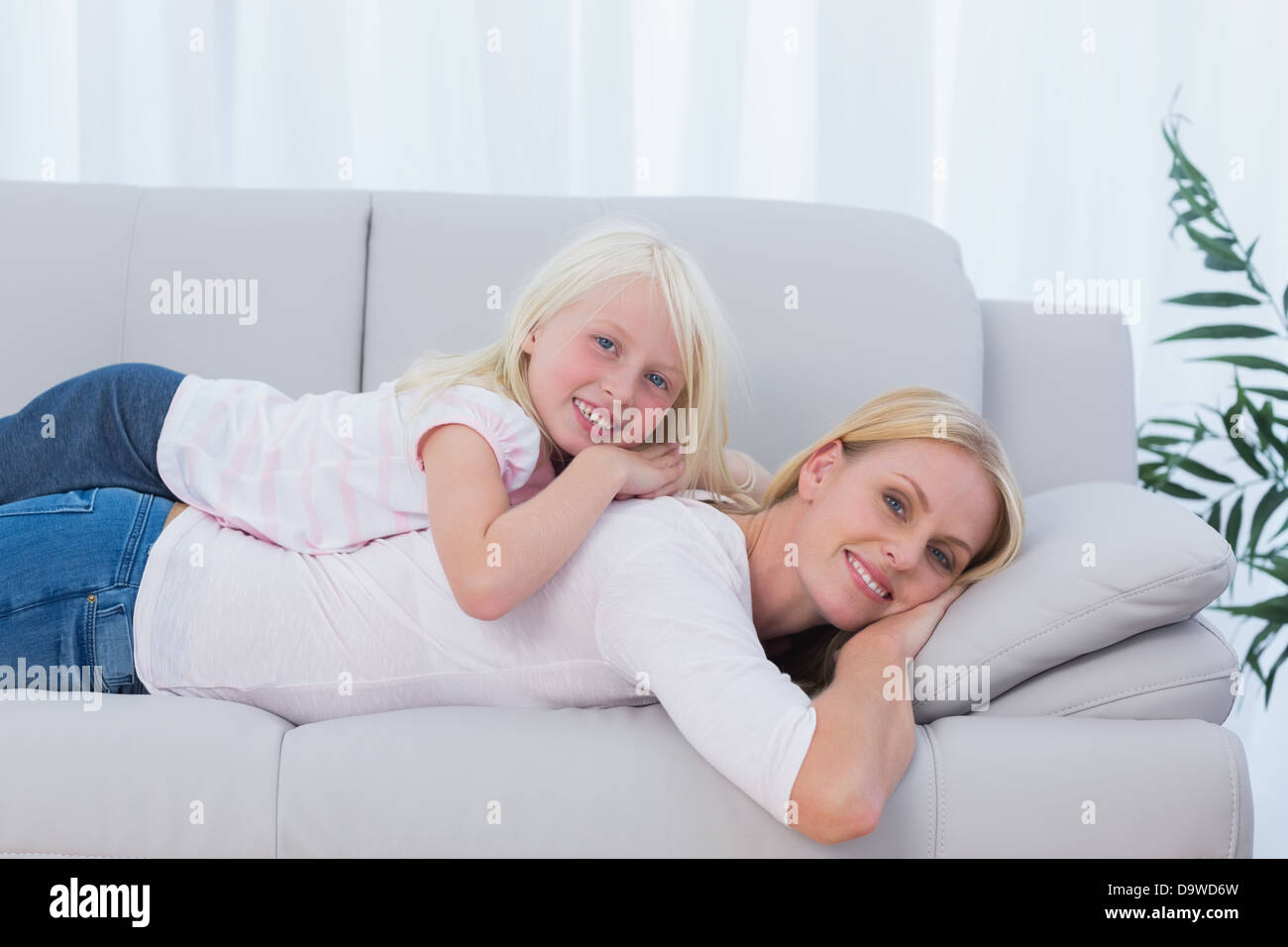 Mother lying on couch with her daughter on her back Stock Photo