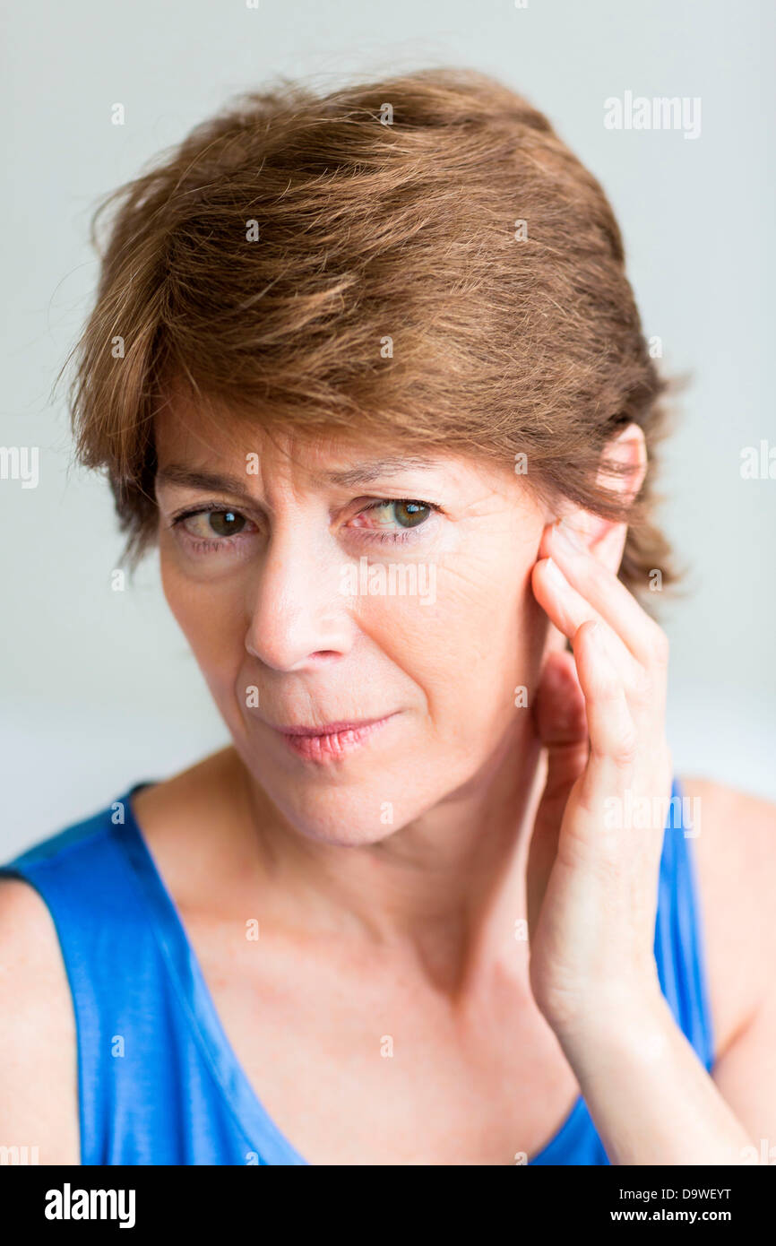 Senior woman holds her hand to her painful ear Stock Photo