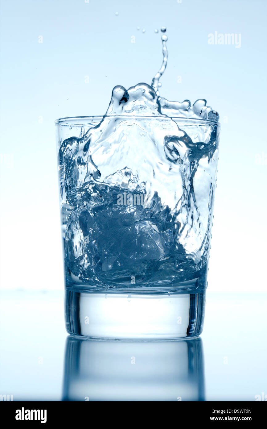 Ice Cube Falling into a Glass of Water Splashing Surface Stock Photo ...