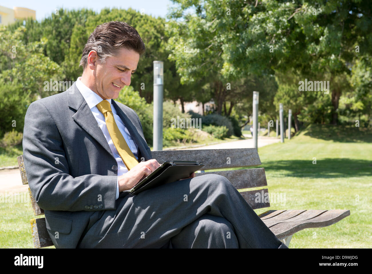 Businessman sitting in the park outdoors with a tablet Stock Photo - Alamy