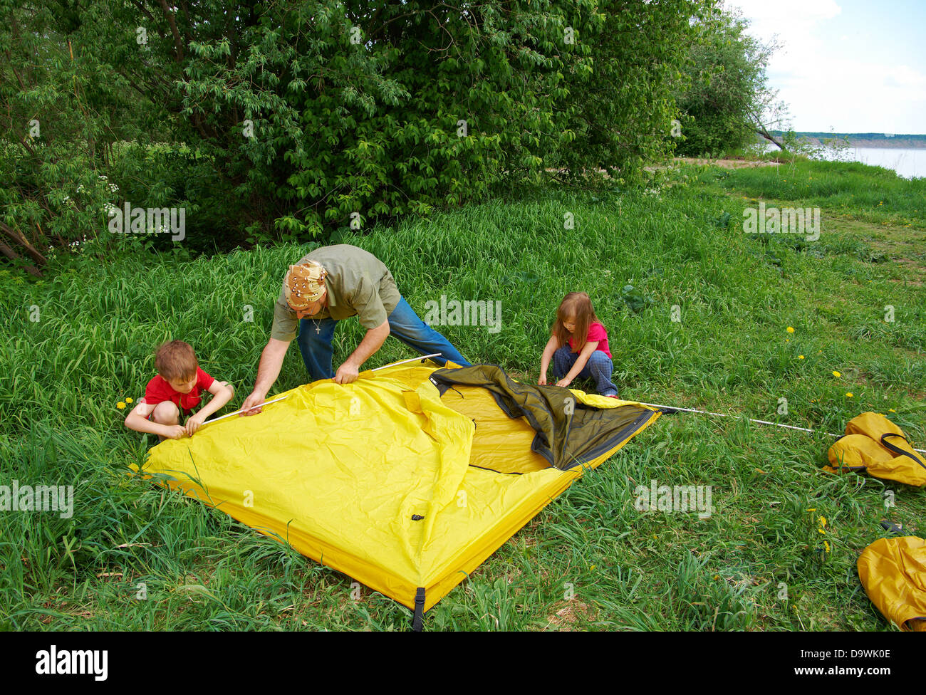 happy Father with children installing their tent on camping site.  Stock Photo