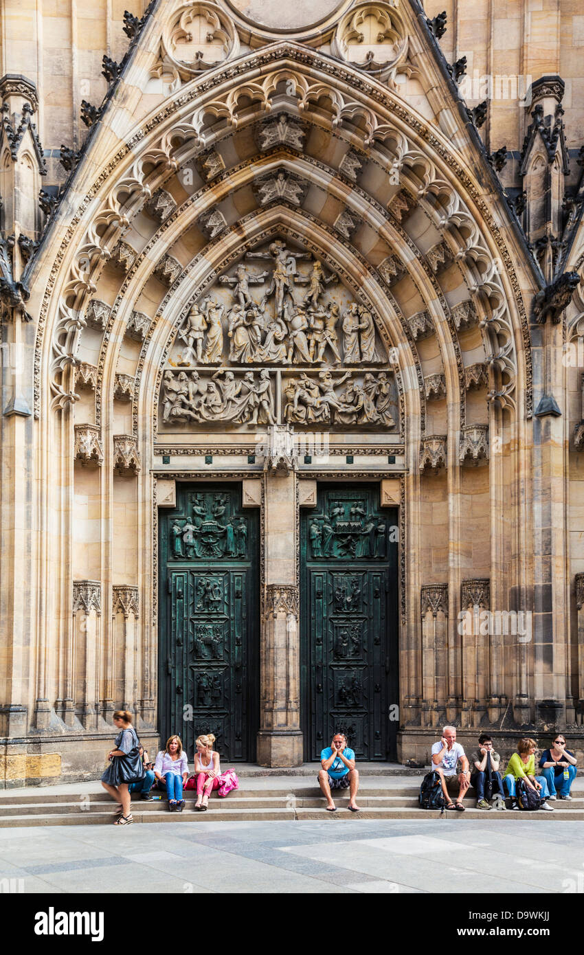 Tourists sitting in front of the medieval gothic front facade of St Vitus Cathedral in Prague. Stock Photo