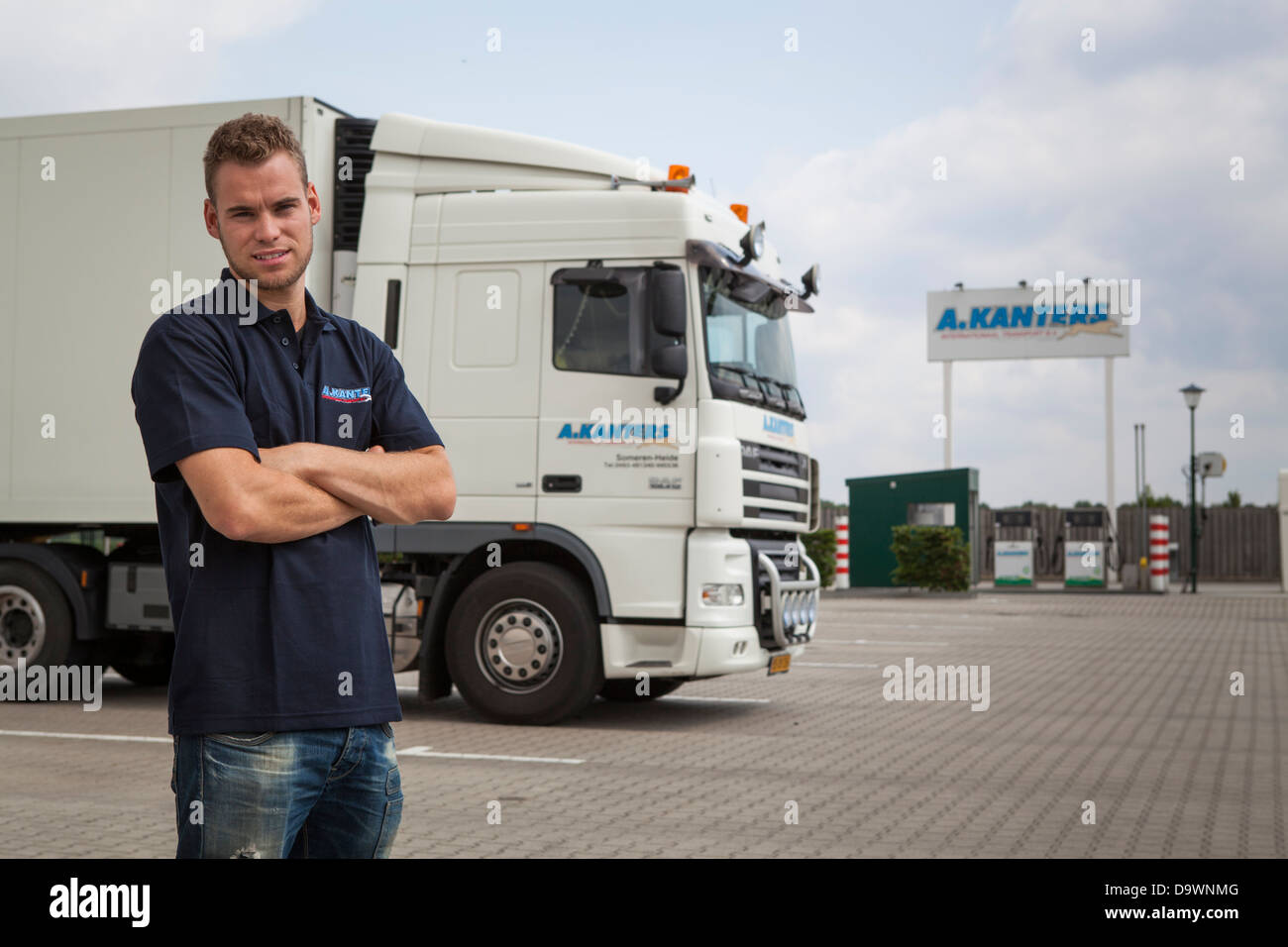 Proud driver posing in front of a truck with the company petrol station in the background Stock Photo