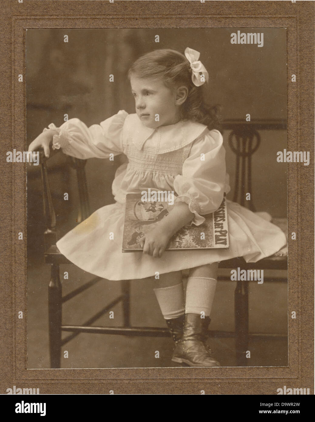 Original early 1900's Edwardian studio portrait of young girl holding a book, circa 1904. U.K. Stock Photo