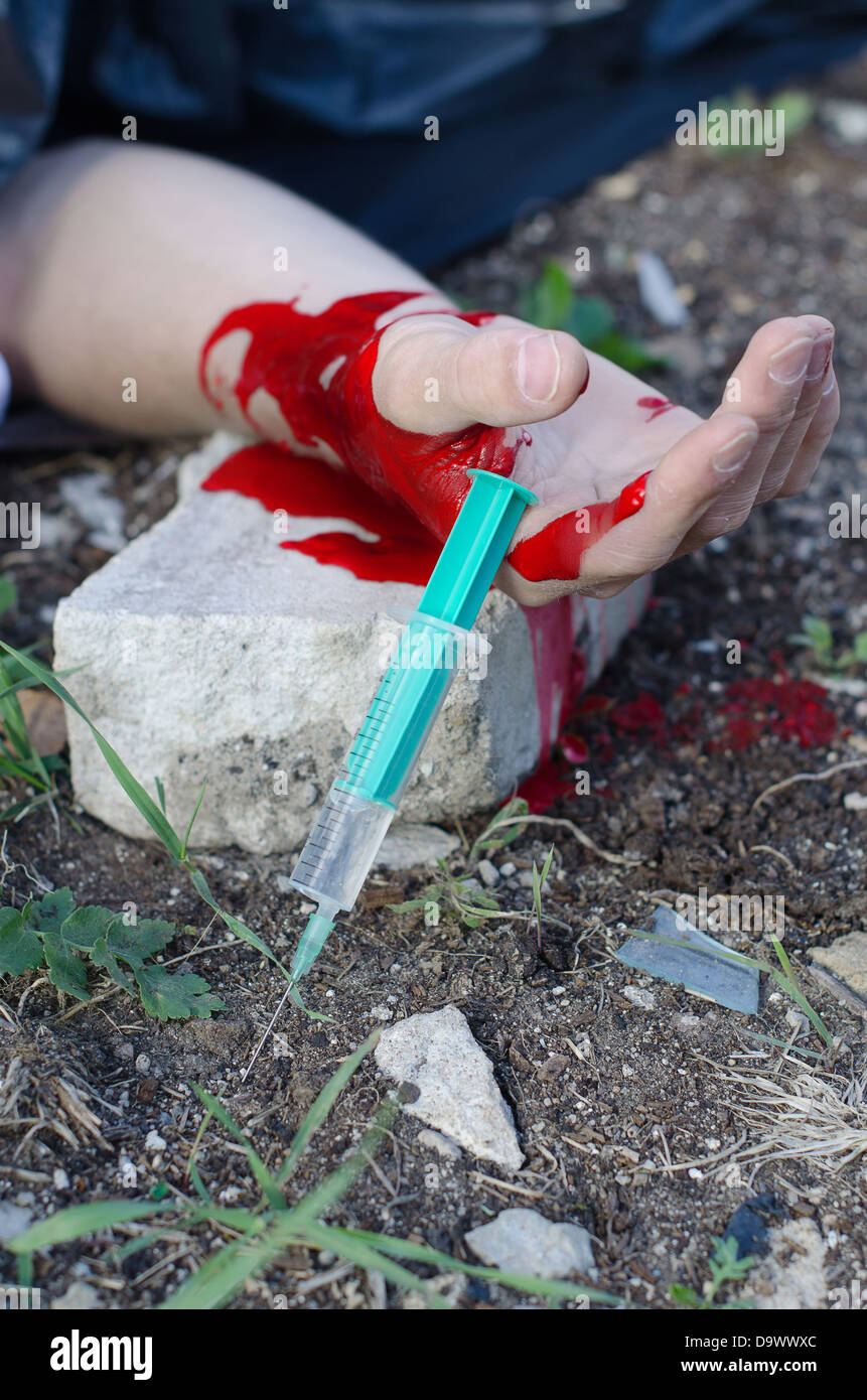 Bloody hand and syringe near it. Crime scene Stock Photo