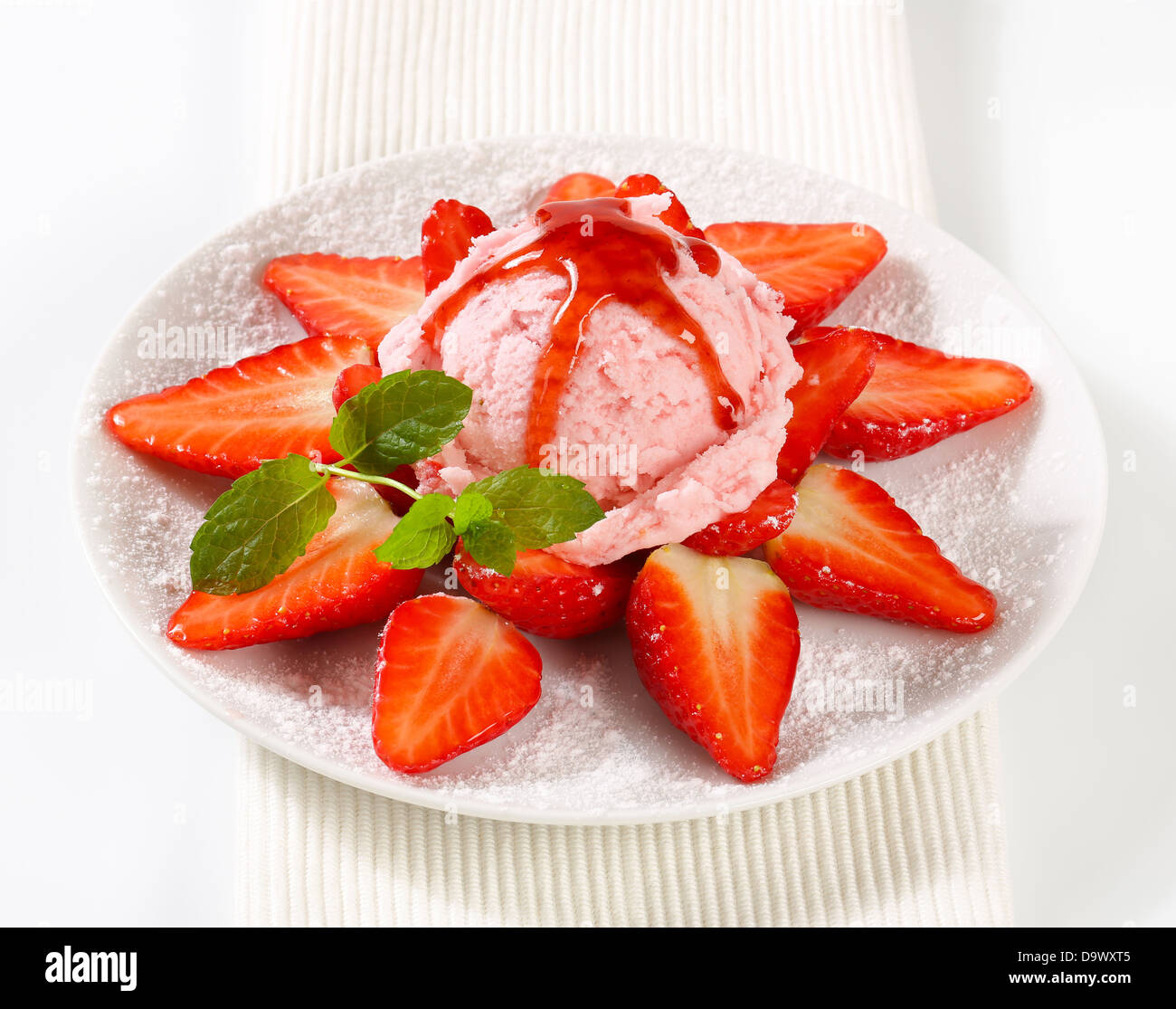 Fresh strawberries arranged around scoop of pink ice cream Stock Photo