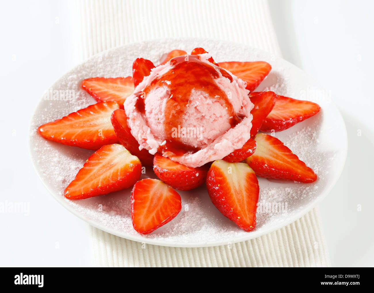 Fresh strawberries arranged around scoop of pink ice cream Stock Photo