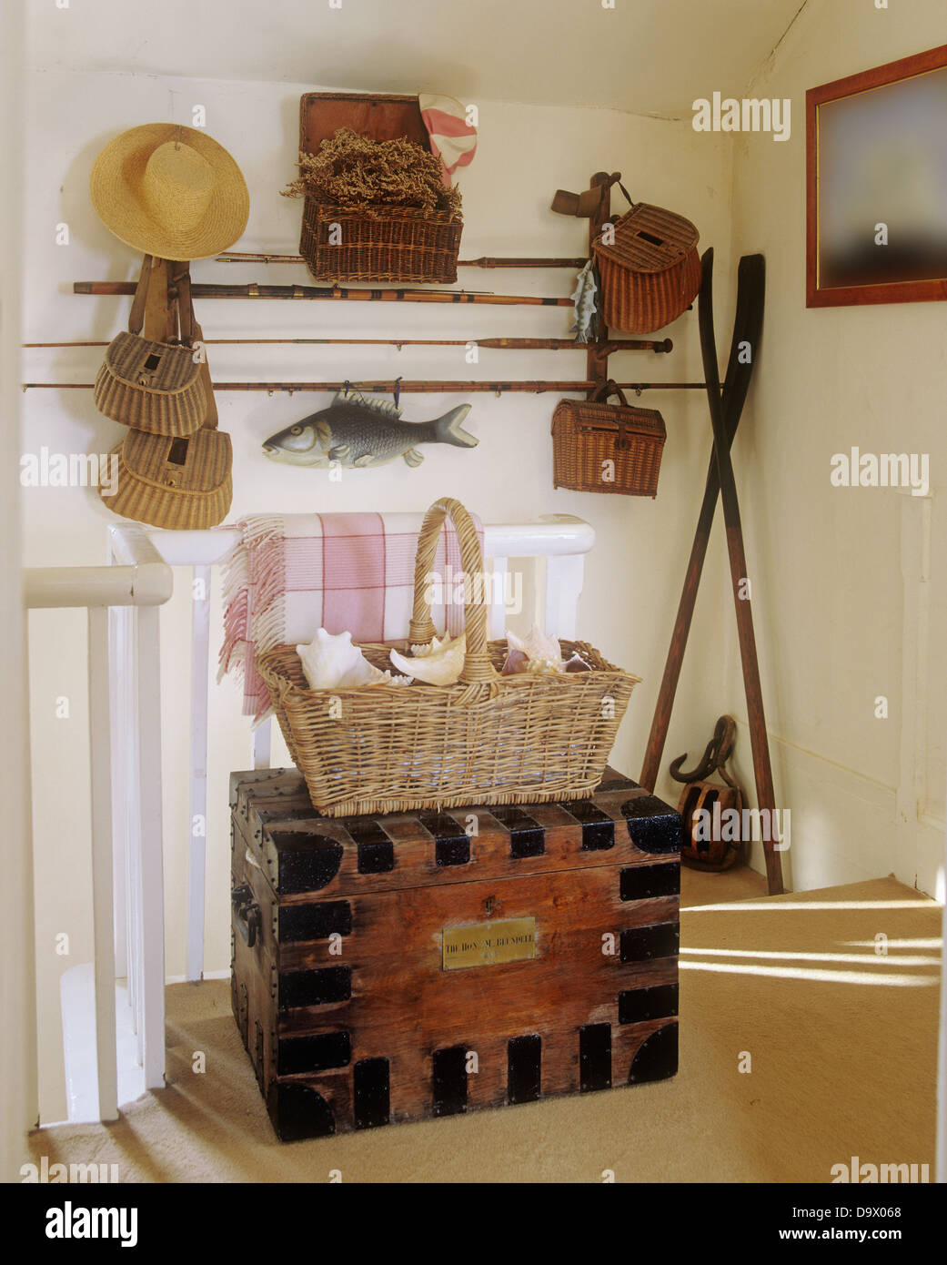 Fishing rods and equipment on wall above large basket on old painted chest  on cottage landing Stock Photo - Alamy
