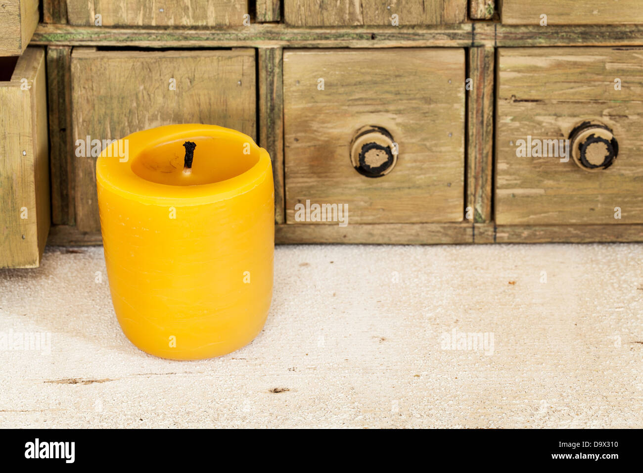 bee wax candle in retro setting with a primitive apothecary drawer cabinet Stock Photo