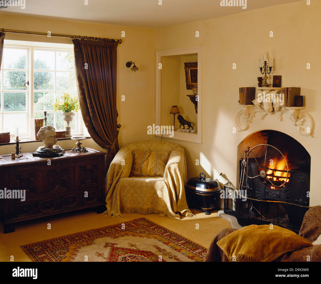 Small alcove above armchair with cream throw beside fireplace with lit