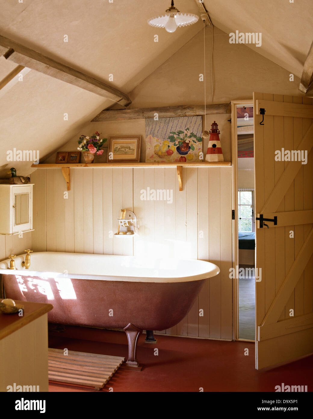 Roll-top bath in small attic bathroom with tongue+groove paneling Stock Photo