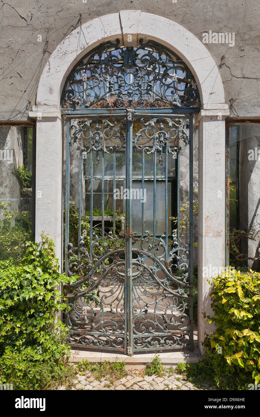 Vintage ornate dilapidated wrought iron gate entrance to a garden greenhouse Stock Photo