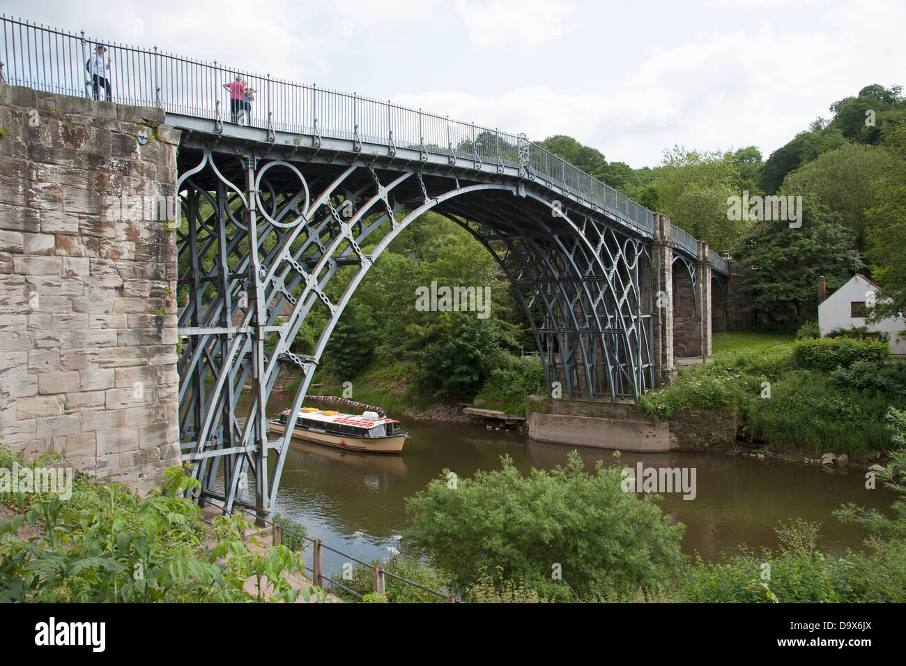 Historic Iron Bridge spans River Severn at Ironbridge in Shropshire England  A river cruise boat passing below the famous bridge Stock Photo