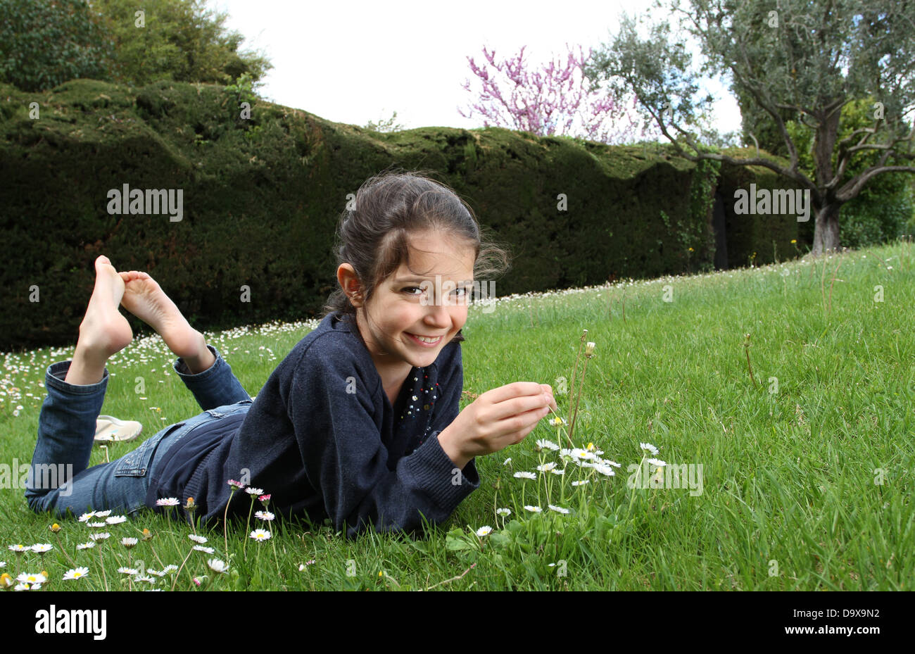 Young girl posing in a garden lying on the lawn Stock Photo