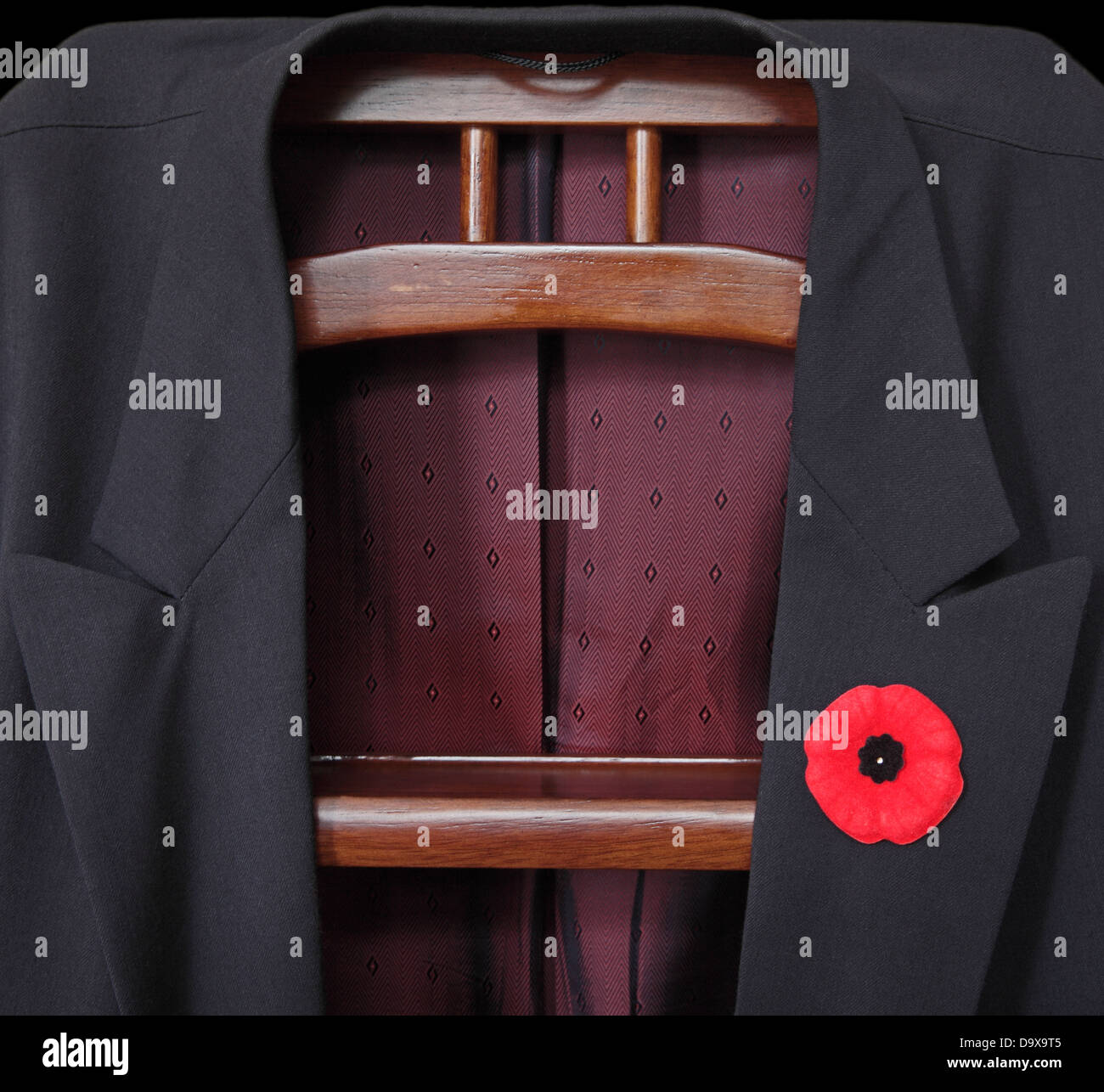 A suit jacket is placed on the jack. A poppy is attached to the lapel. Low key Stock Photo