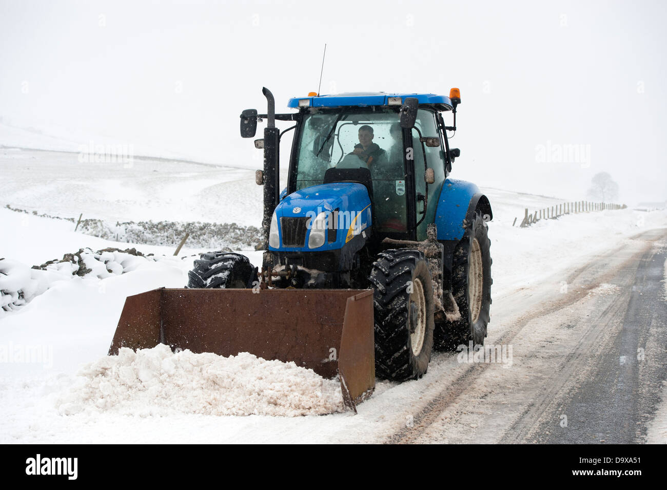 Farmer on a New Holland tractor clearing snow oiff rural road after a