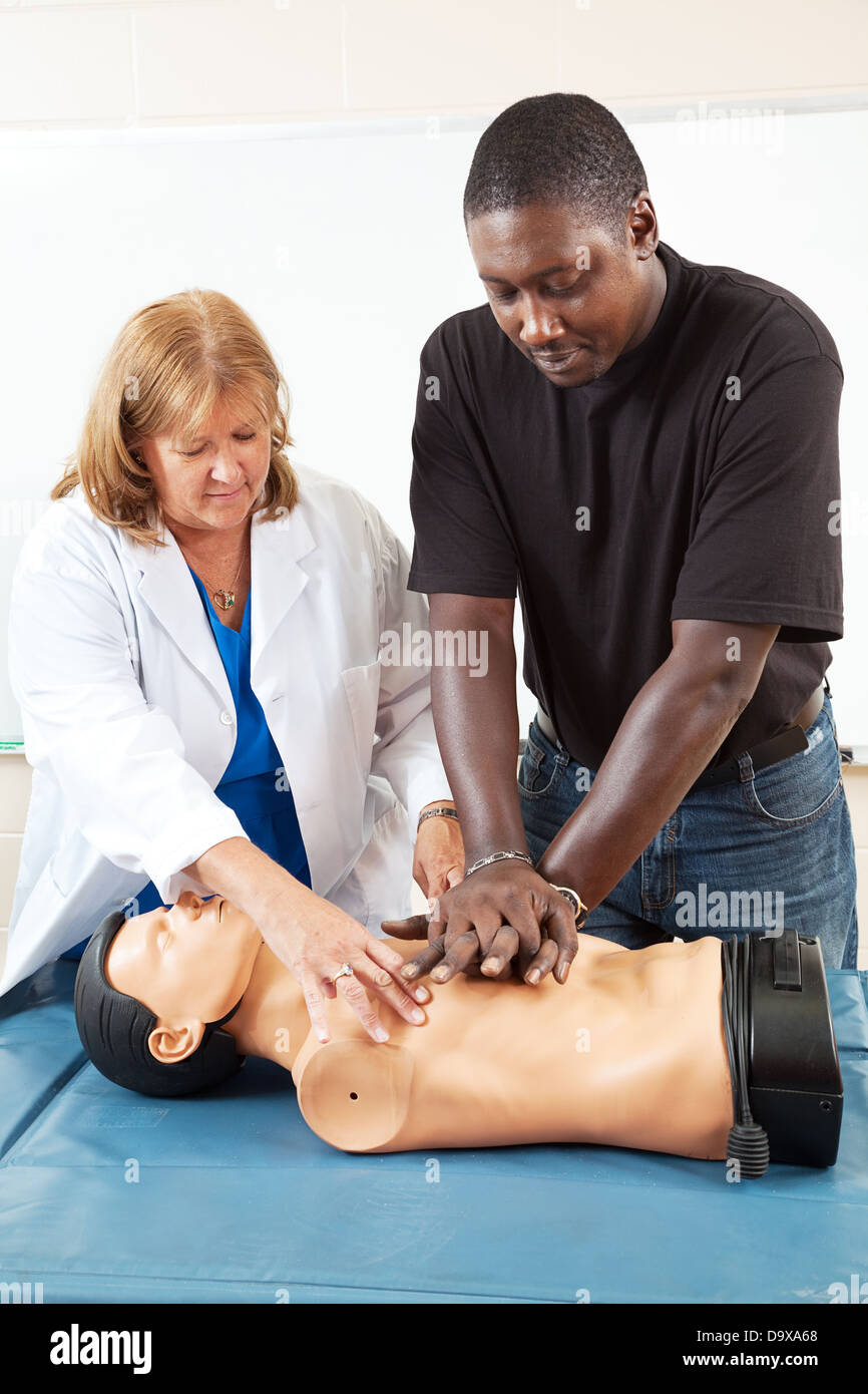 Doctor or nurse instructs an adult student in CPR life-saving techniques. Stock Photo