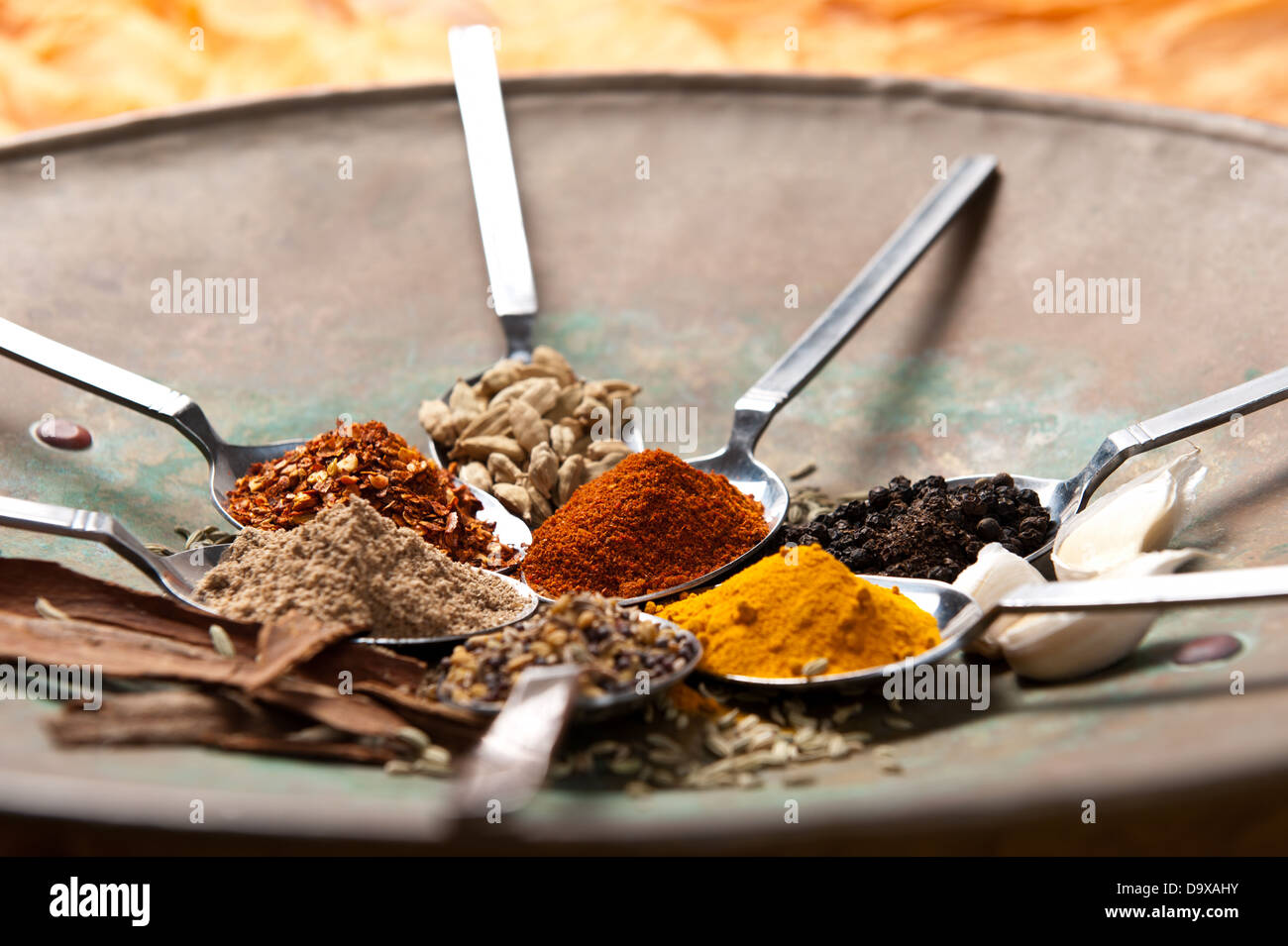 7 Table spoons arranged with different spices in a round Indian dish. Stock Photo