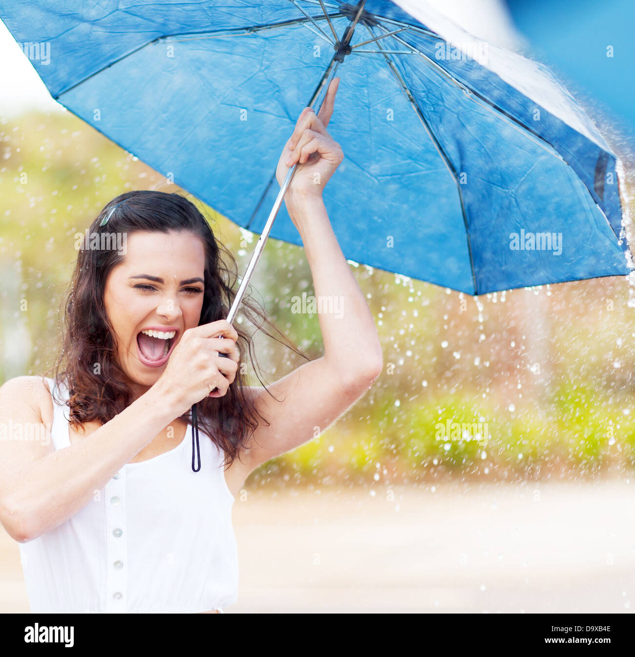 playful young woman holding umbrella in the rain Stock Photo