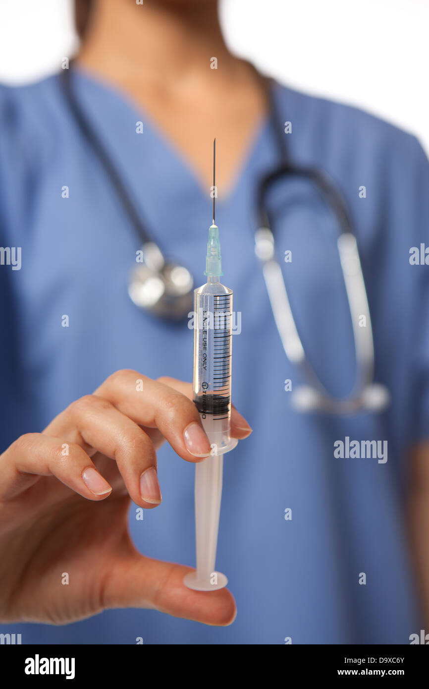 Female nurse doctor holding syringe with needle in front of themselves Stock Photo