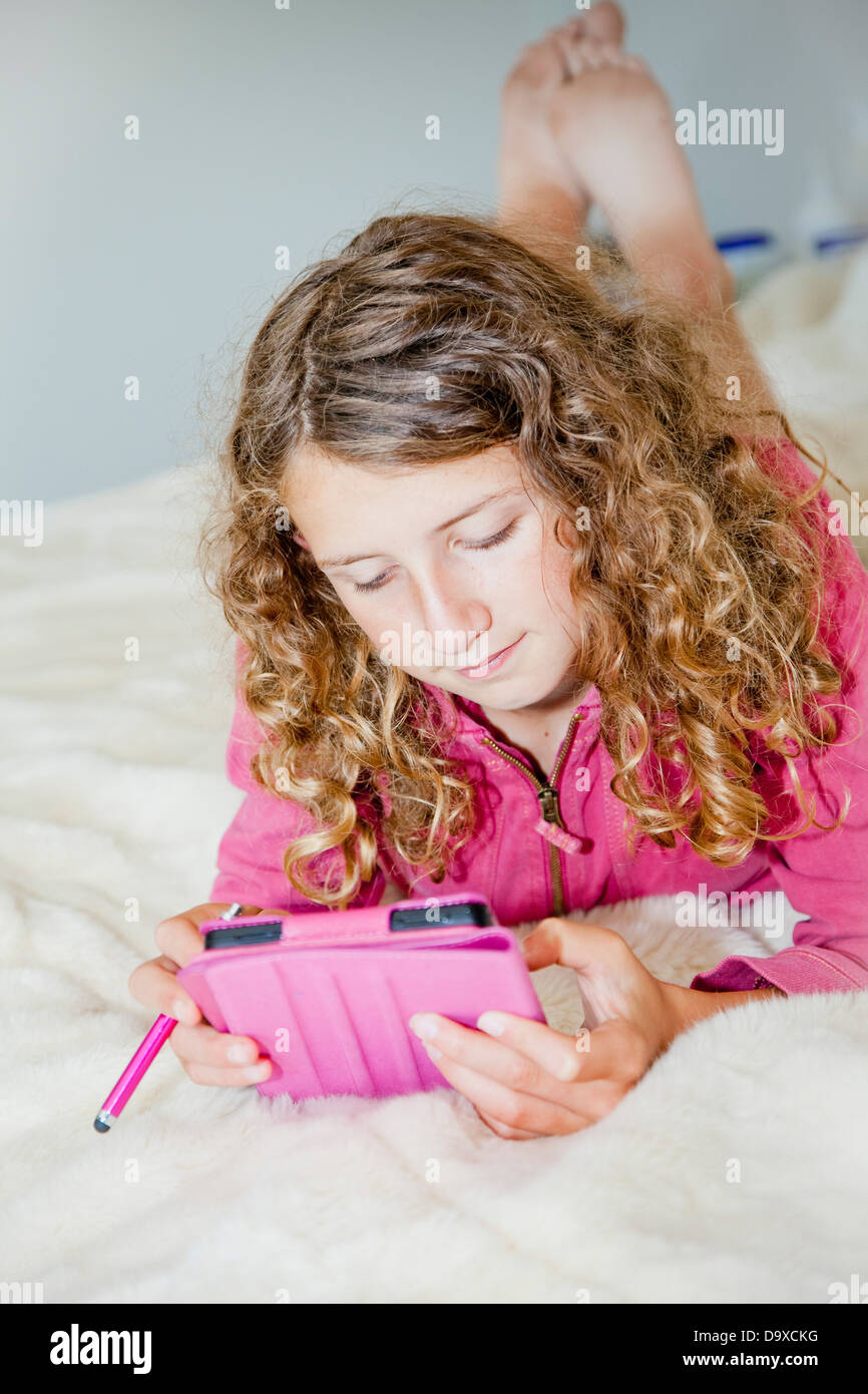 Teen girl on bed with tablet Stock Photo