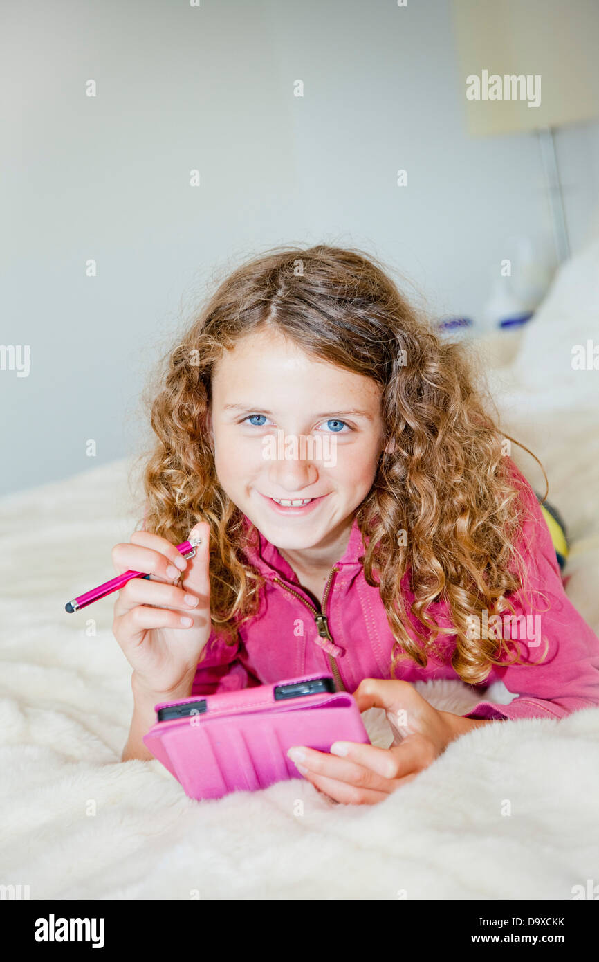 Teen girl on bed with tablet Stock Photo