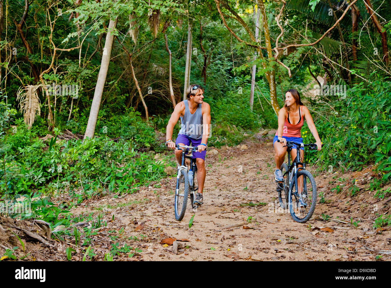 Couple riding bicycles on jungle path Stock Photo