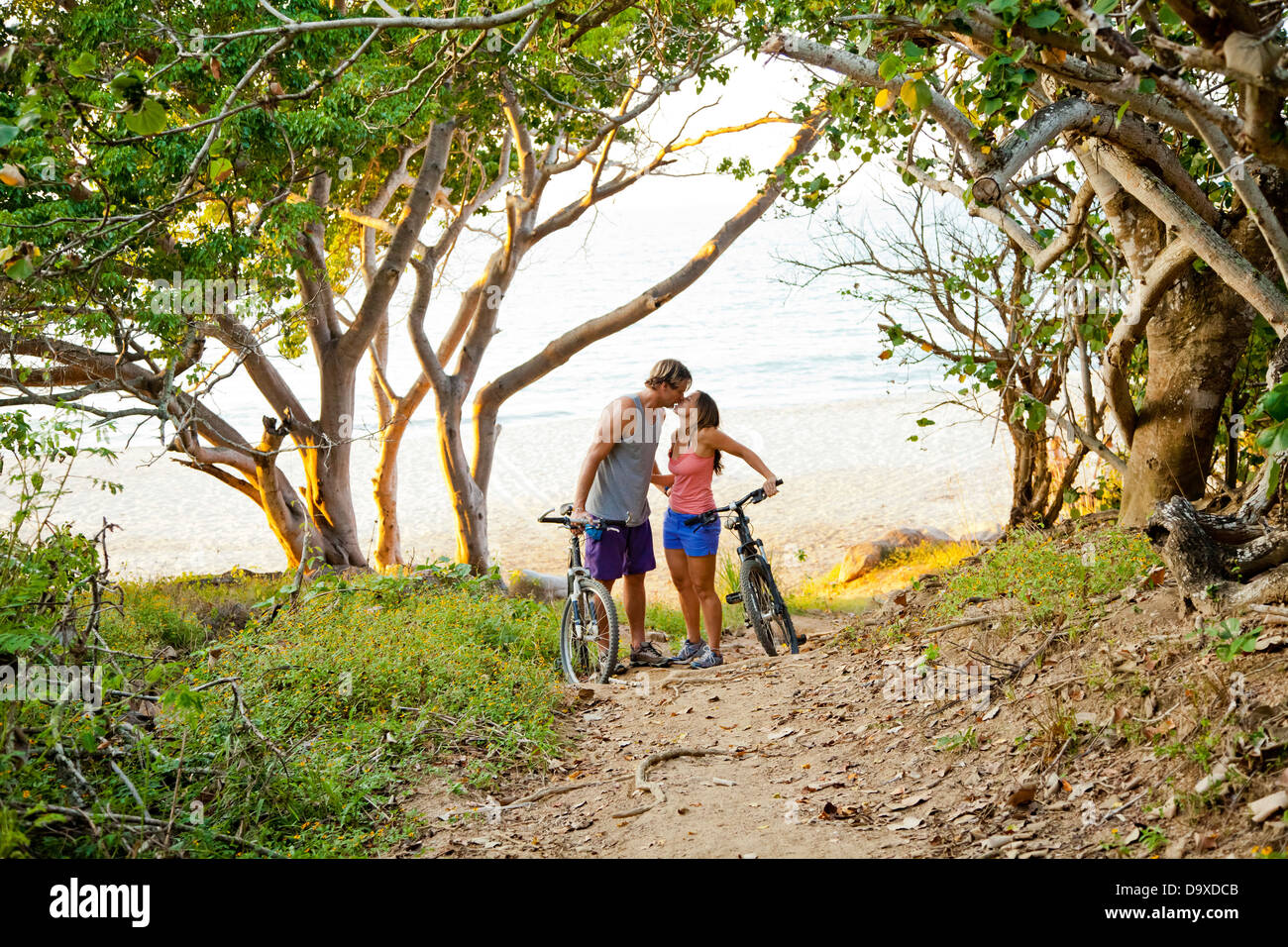 Couple riding bicycles on path to beach Stock Photo