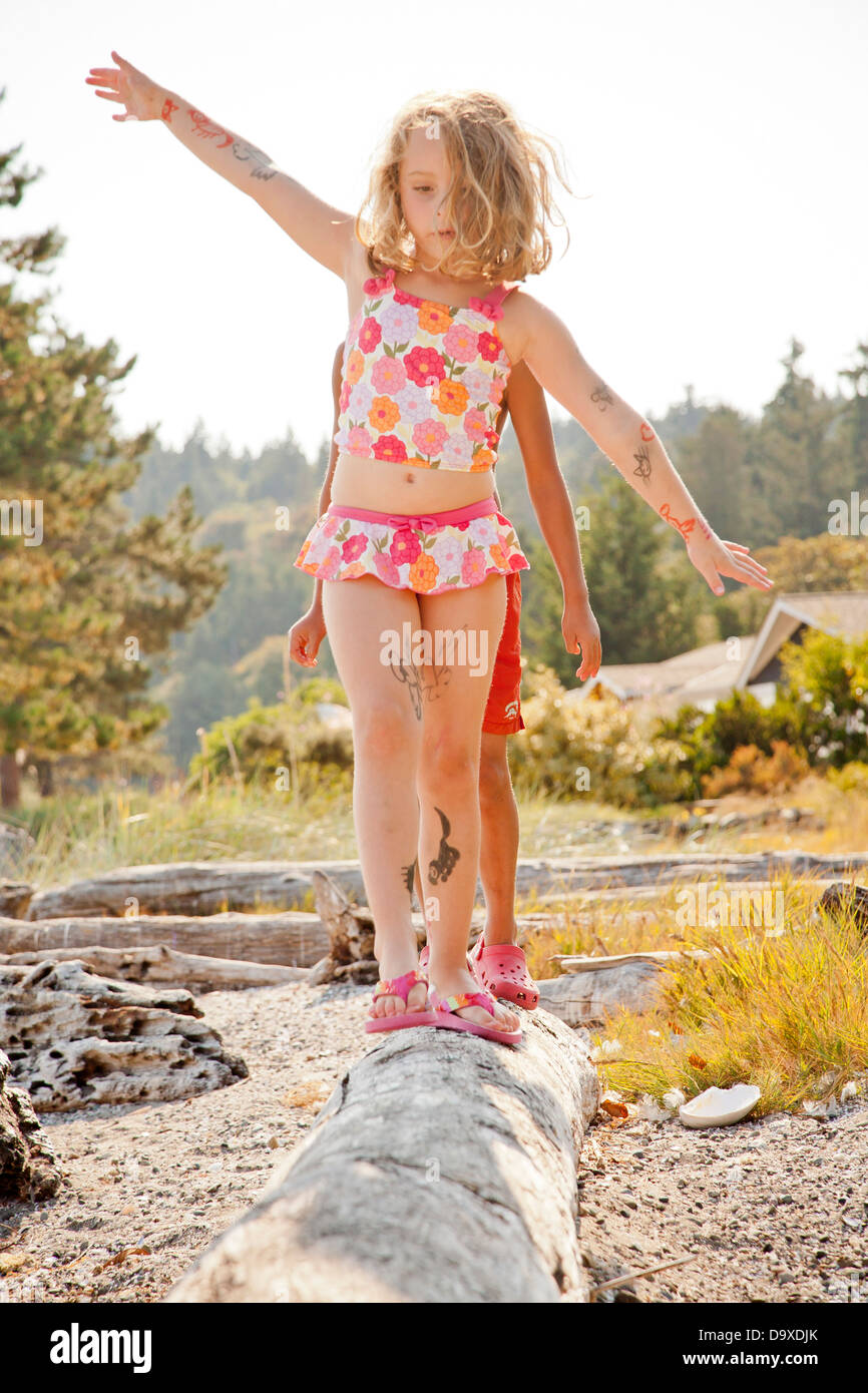 Two children balancing on driftwood log Stock Photo