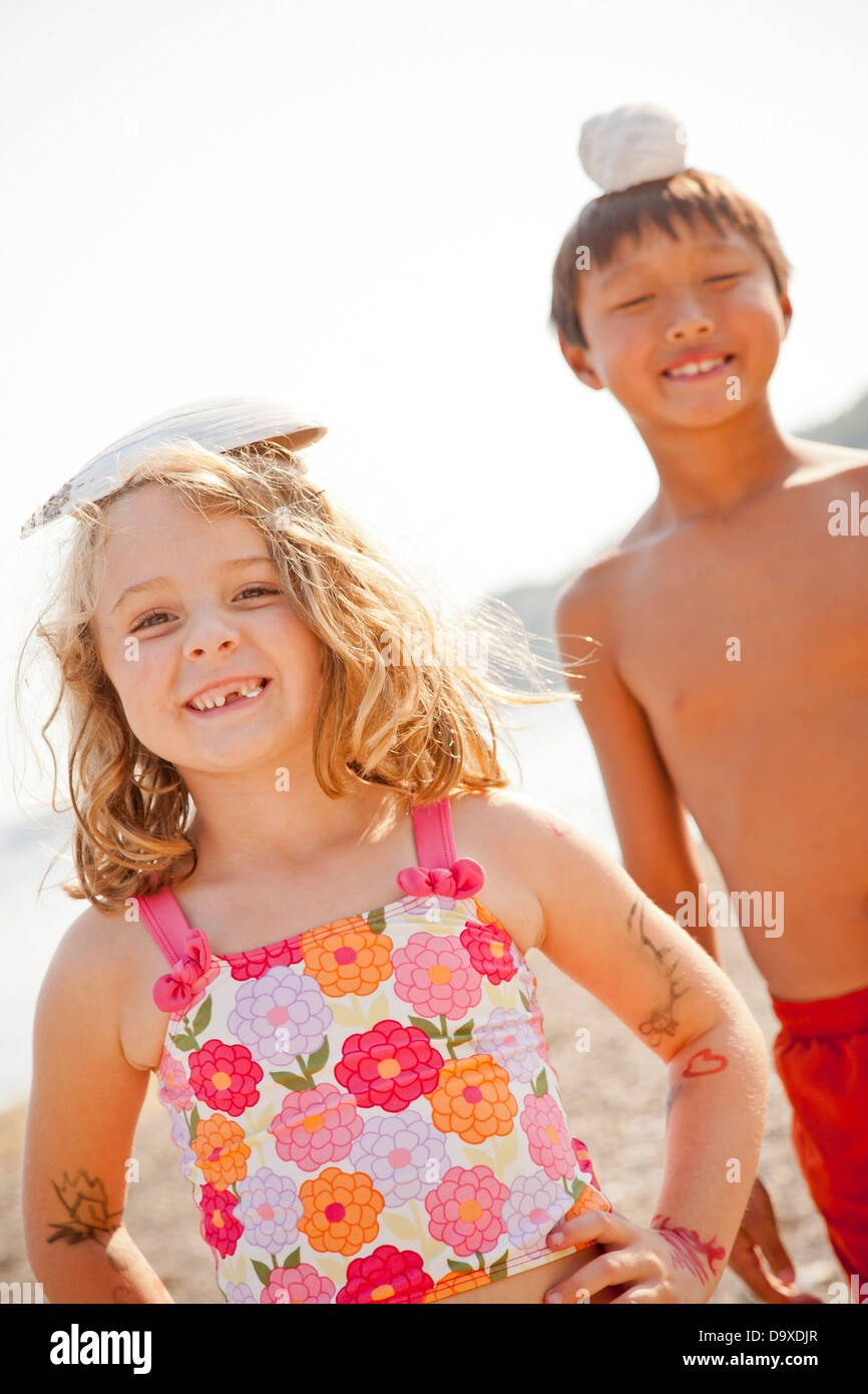 Young boy and girl balancing shells on their heads Stock Photo