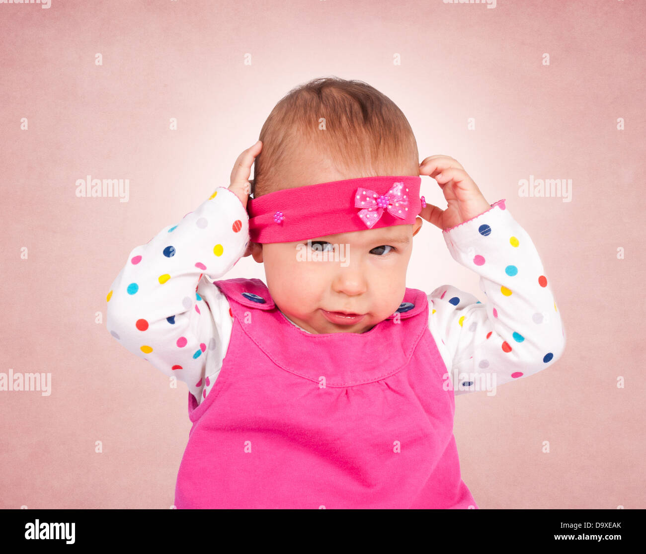 Little baby girl holding hand on her head Stock Photo - Alamy