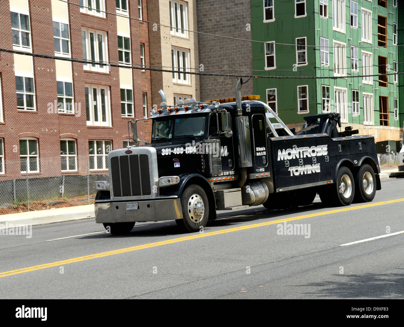 Large tow truck driving down street Stock Photo