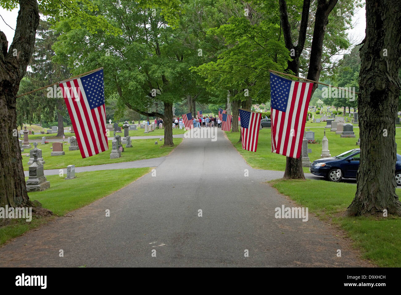 Flags line cemetery on Memorial day where crowd gathers honor fallen soldiers outside Lexington MA on Memorial Day 2011 Stock Photo