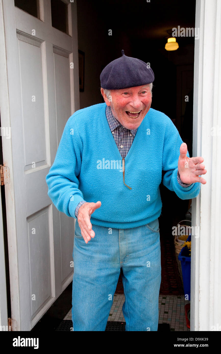 Senior Italian-American man in blue seater matching hat gestures smiles in front his home in historic North End Italian section Stock Photo