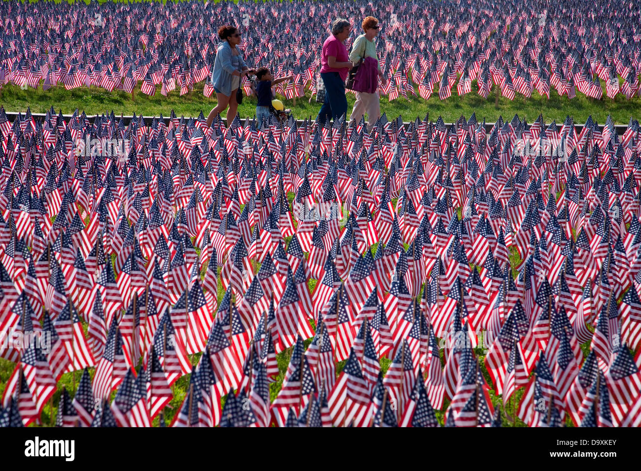 People walk through 20,000 American Flags that are displayed for every resident Massachusetts who died in war over past 100 Stock Photo