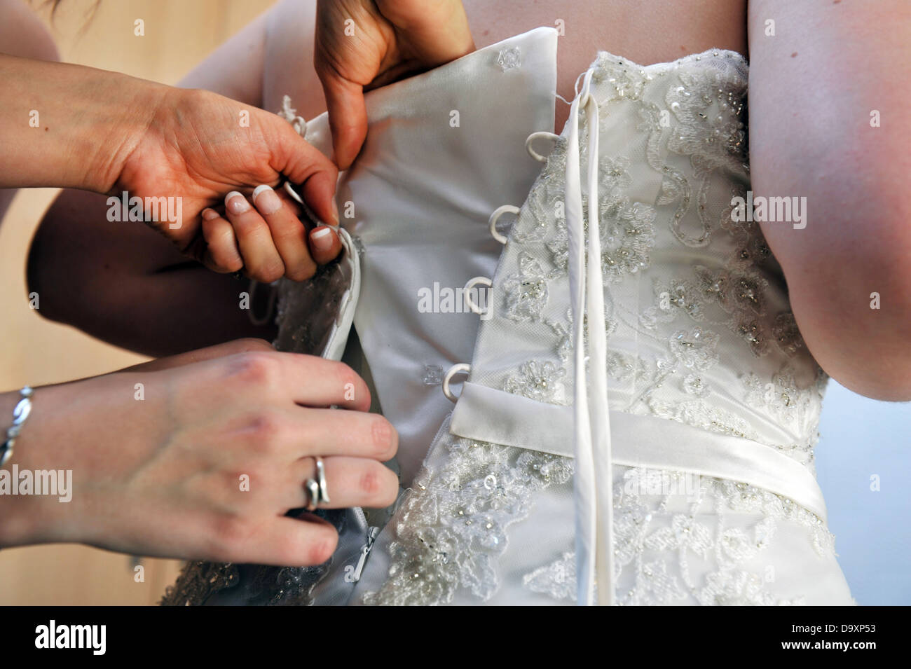 Bride is helped into her wedding dress on her wedding day. Stock Photo
