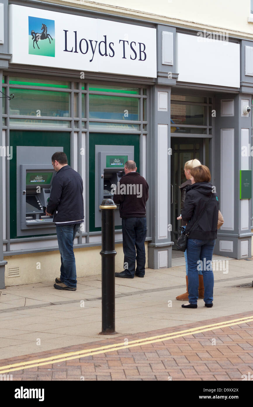 A queue of customers wait at Lloyds TSB cashpoint machines Stock Photo
