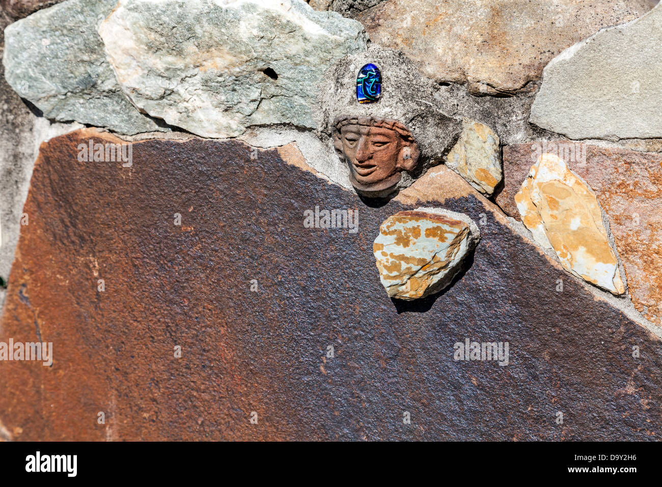 Small carved indian head with blue stone embedded in a stone wall surrounding the children's garden at Kanapaha Gardens. Stock Photo