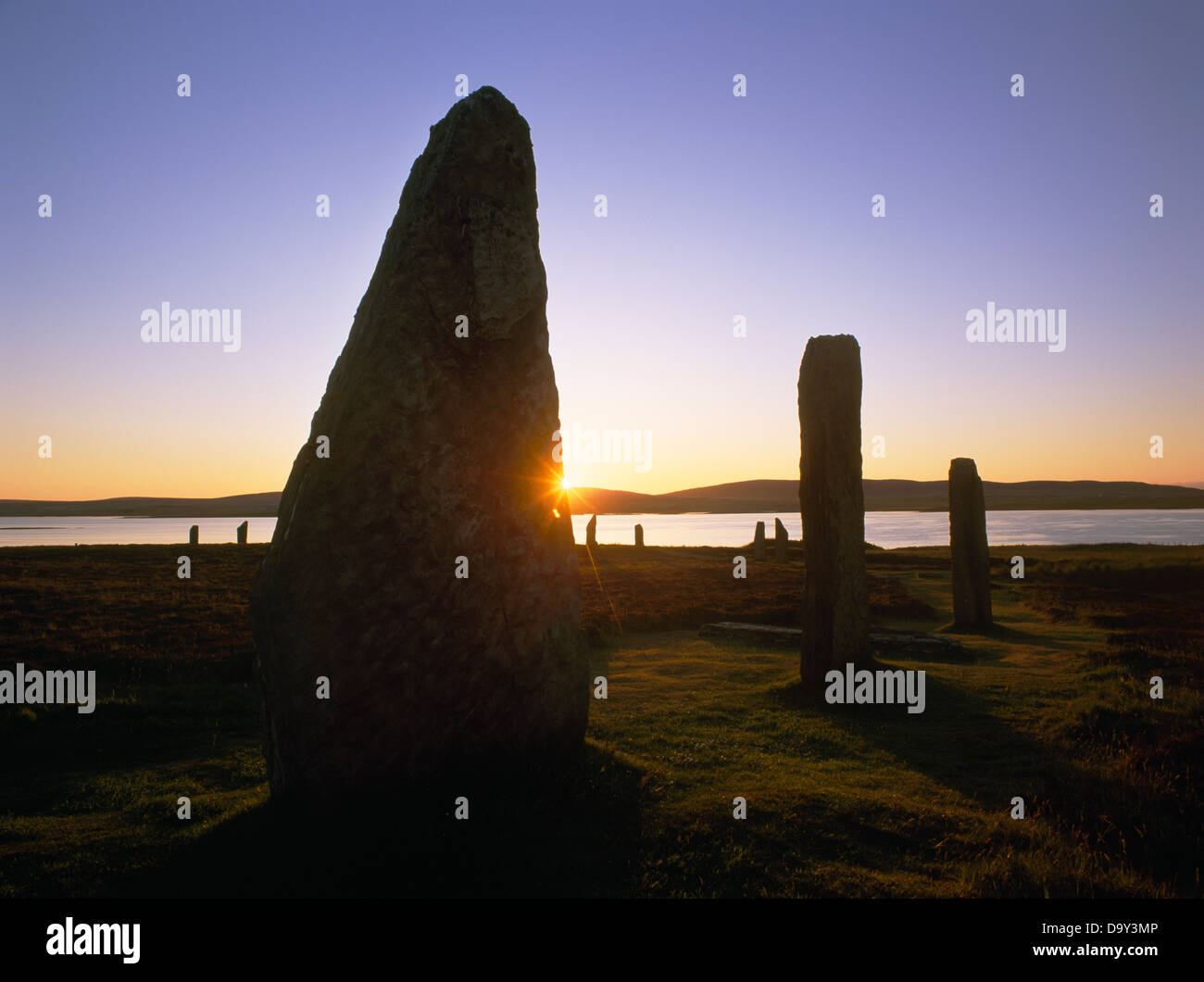 Sunrise at the Ring of Brodgar henge and stone circle, Orkney; looking through the eastern arc of stones to the Loch of Harray Stock Photo