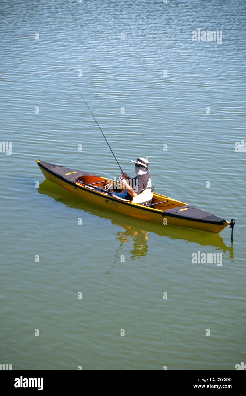 From his canoe, an angler fishes in harsh sun for bass and panfish in a small lake. Stock Photo