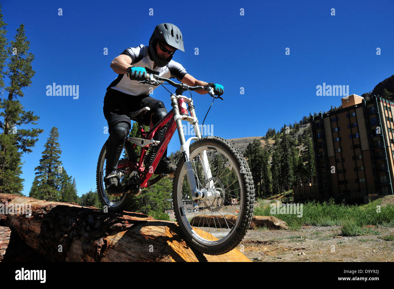A mountain biker performs a log ride on a terrain feature at Kirkwood Mountain Resort, CA. Stock Photo