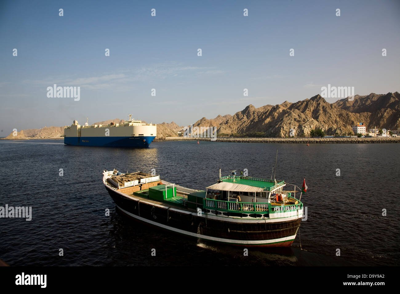 Dhows of traditional design are used for cargo runs and strike quite a contrast with mammoth cargo vessels, Muscat Harbor, Oman Stock Photo