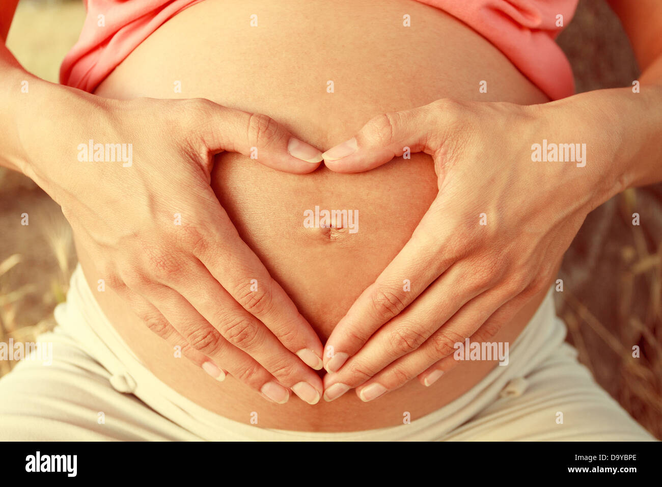 Pregnant woman making heart shape with her hands Stock Photo