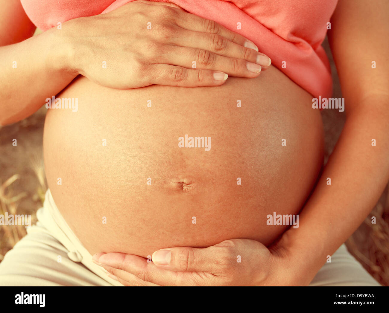 Pregnant woman touching her belly with hands Stock Photo
