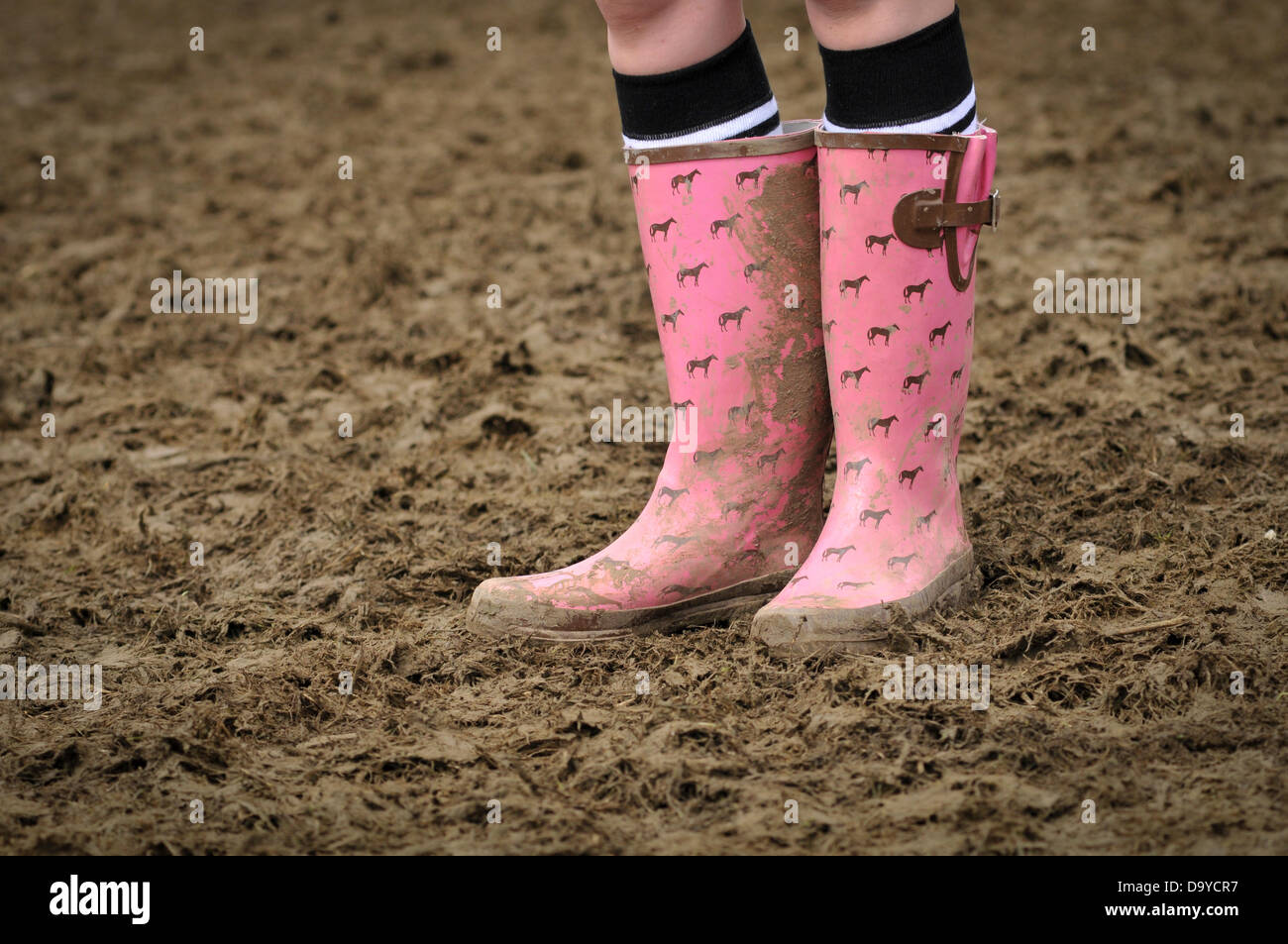 Festival goers wearing wellingtons because of the sticky mud that covers  the ground after a couple hours of rain yesterday. Glastonbury Festival  takes place at Worthy Farm, Pilton Somerset. GLASTONBURY MUSIC FESTIVAL