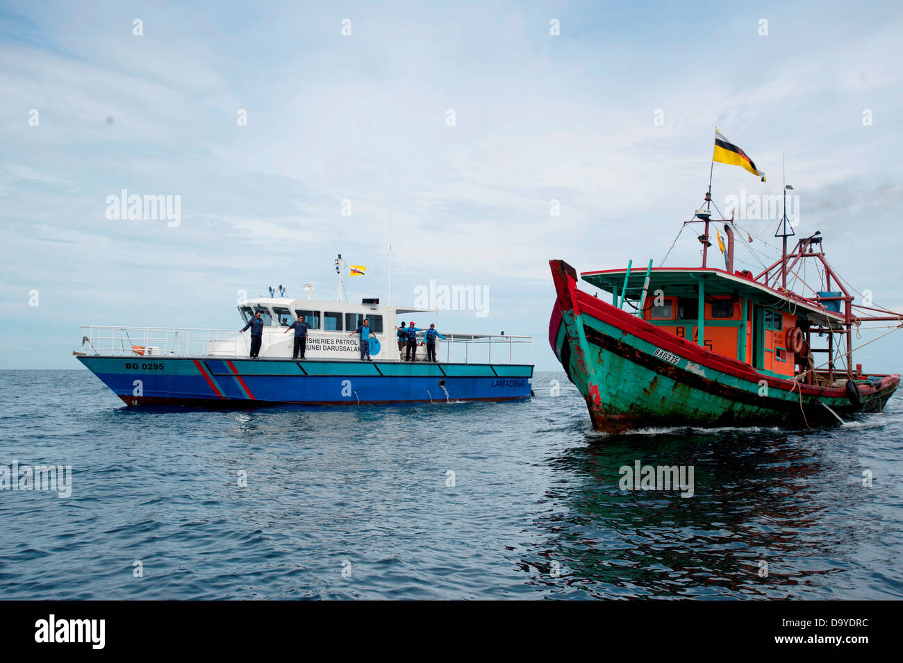 Fisheries department officials pull up next to a trawler hauling net to conduct a spot check, Brunei Stock Photo