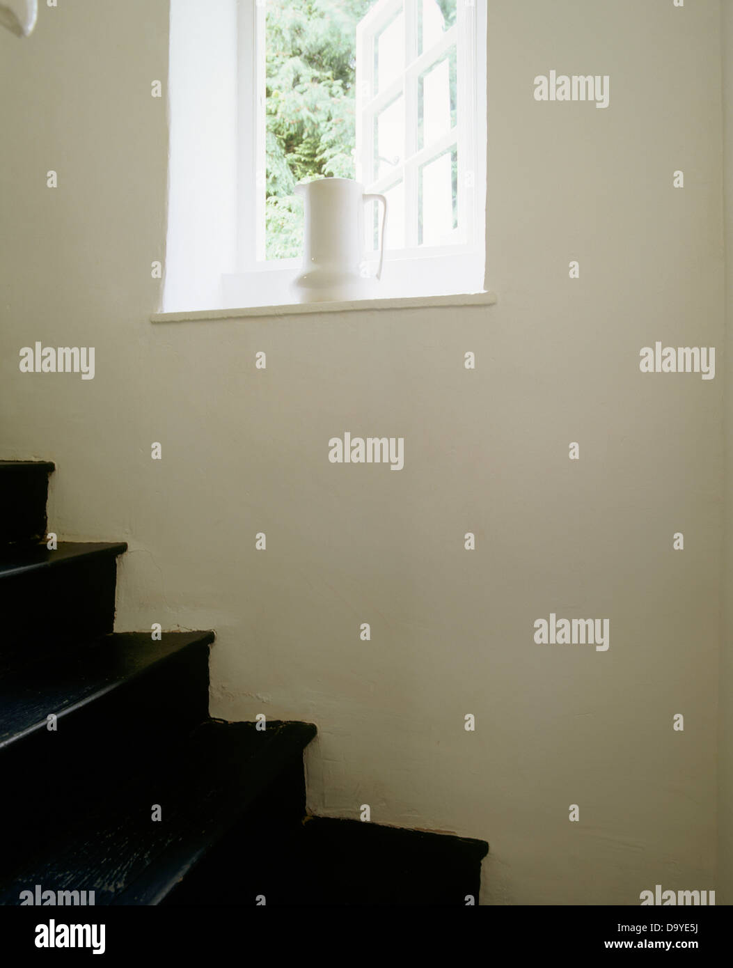 White jug on windowsill of open window above black painted wooden ...